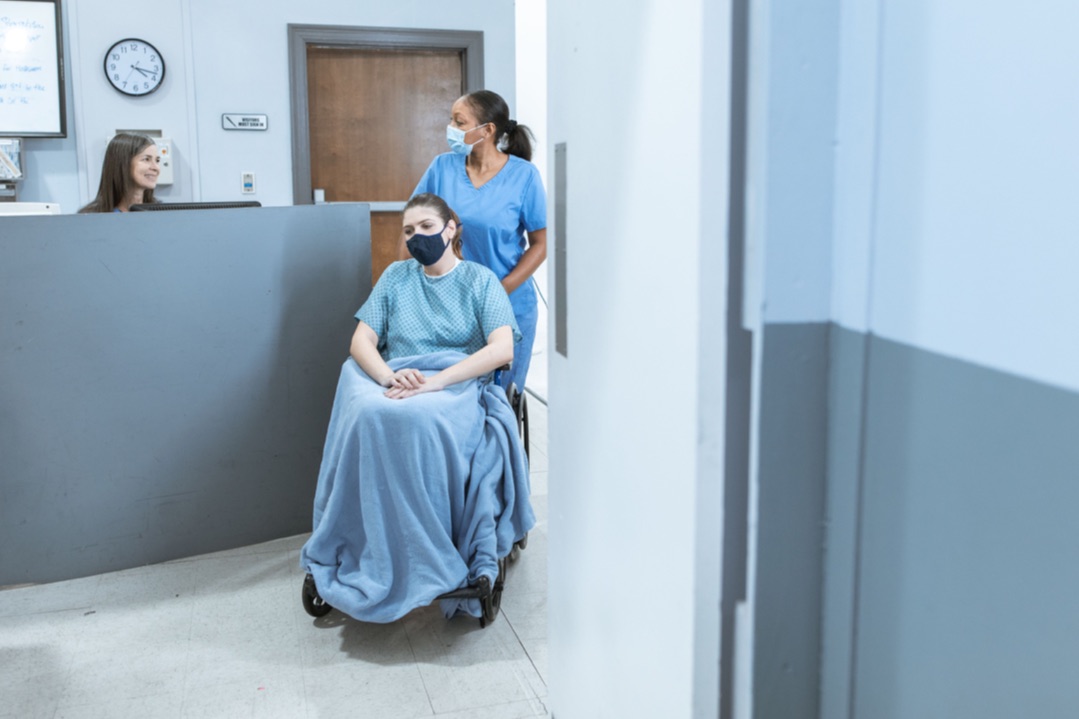 Clinic reception area with a patient using a wheelchair and a healthcare worker nearby